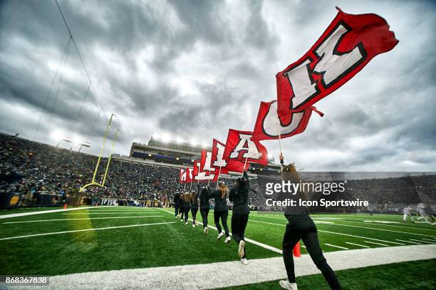 North Carolina State Wolfpack cheerleaders run out with flags spelling the word Wolfpack after a touchdown during the college football game between...