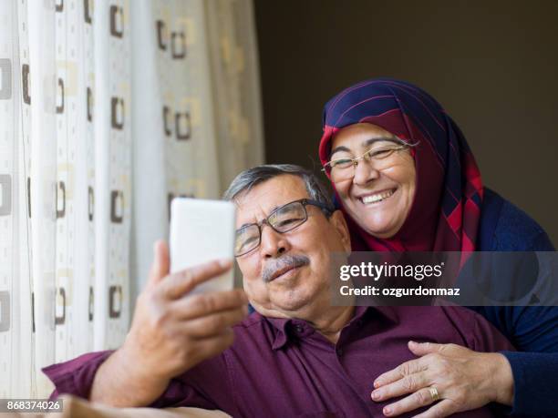 senior paar gebruik mobiele telefoon - headscarf home stockfoto's en -beelden