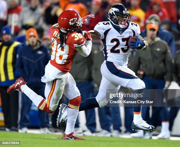 Denver Broncos running back Devontae Booker stiff arms Kansas City Chiefs free safety Ron Parker on a first down run in the third quarter during...