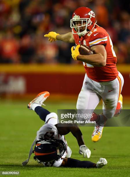 Tight end Travis Kelce of the Kansas City Chiefs carries the ball after making a catch as free safety Bradley Roby of the Denver Broncos defends...