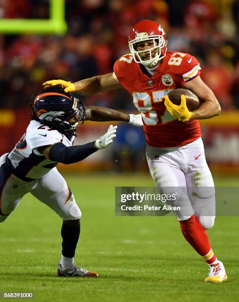 Tight end Travis Kelce of the Kansas City Chiefs carries the ball after making a catch as free safety Bradley Roby of the Denver Broncos defends...