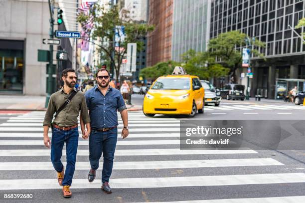 walking mature adult gay men crossing the street while holding hands in new york - couple crossing street stock pictures, royalty-free photos & images