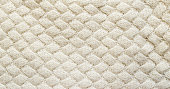 White knitted carpet closeup. Textile texture off white background. Detailed warm yarn background. Knit cashmere beige wool. Natural woolen fabric, sweater fragment.