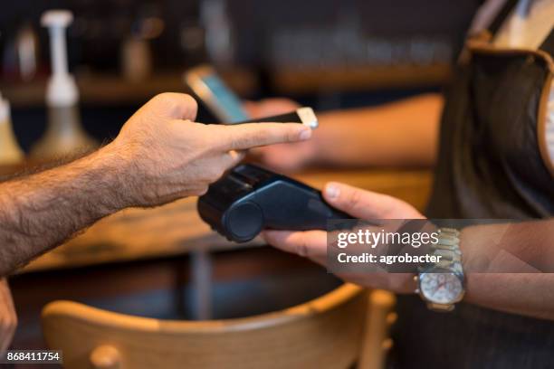 man met nfc technologie op slimme telefoon te betalen - dichterbij komen stockfoto's en -beelden
