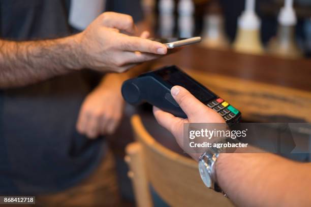 man met nfc technologie op slimme telefoon te betalen - dichterbij komen stockfoto's en -beelden