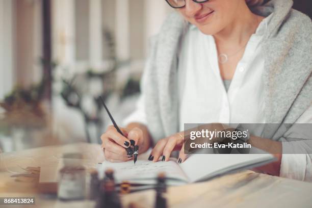 junge geschäftsfrau schreibt in ein persönlicher organizer - kalligraphieren stock-fotos und bilder