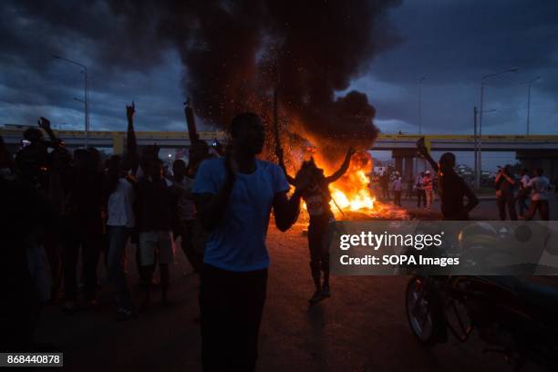 Protesters seen starting a fire by burning tyres and dance around it during a protest in Kisumu. After the IEBC announced the new president elect of...