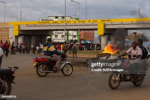 Motorcycle and people seen passing front of the fire that was started by demonstrators during a protest. After the IEBC announced the new president...