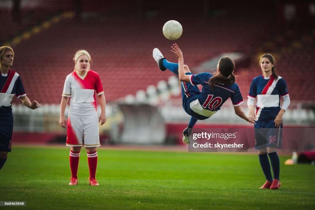 Delantero hábil fútbol femenino haciendo patada de bicicleta durante el juego.