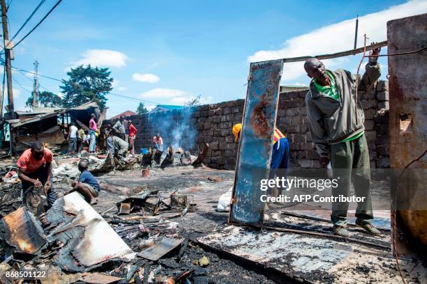 Kibera residents clean up and remove debris from a shop that was burned down the previous evening during clashes between Kenyan Opposition Party...