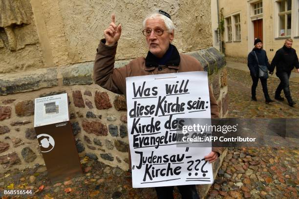 Lone protester displays a placard reading "What does this Church want to be: Gospel Church or 'Jew-Pig' Church???" as he protests against the...