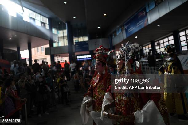 Commuters watch as artists from the Malaysian Teochew Puppet and Opera House perform at the Masjid Jamek station in Kuala Lumpur on October 31, 2017....