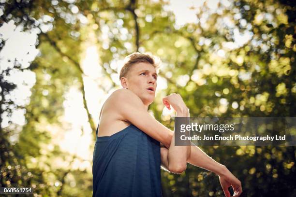 man stretching before run in woods - jon enoch stock-fotos und bilder