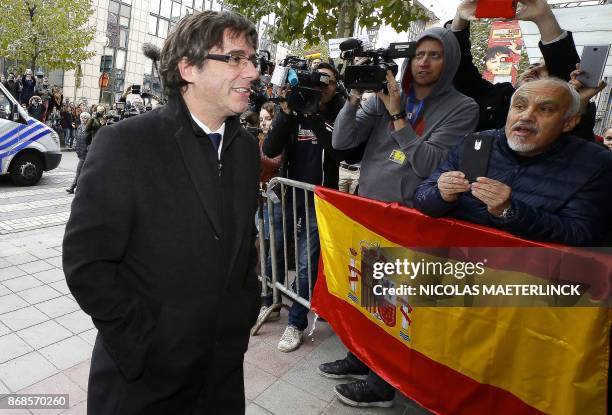 Dismissed Catalonia's leader Carles Puigdemont walks past Spanish flag as he arrives to address a press conference at The Press Club in Brussels on...