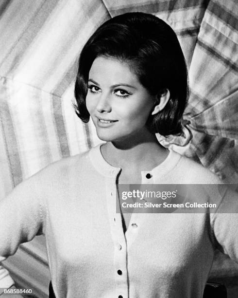Portrait of Italian actress Claudia Cardinale as she poses in front of an open umbrella, 1960s.