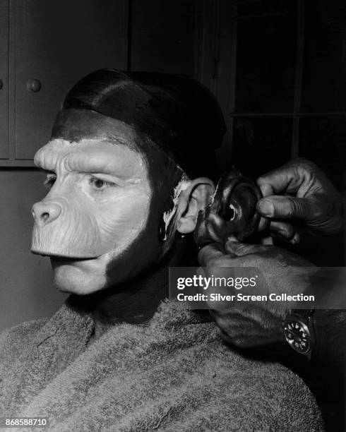 Portrait of American makeup artist Fred Blau works on English-American actor Roddy McDowall to transform him into character backstage for an episode...