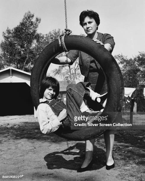 American actress Mary Badham sits in a tire swing held by Pulitzer Prize winning author Harper Lee on the set of the film version of the latter's...