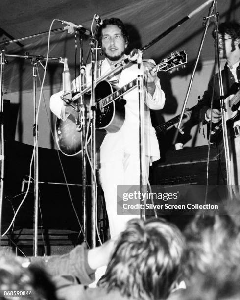 American musician Bob Dylan plays acoustic guitar as he performs with the Band onstage during the Isle of Wight Festival, Wootton, Isle of Wight,...