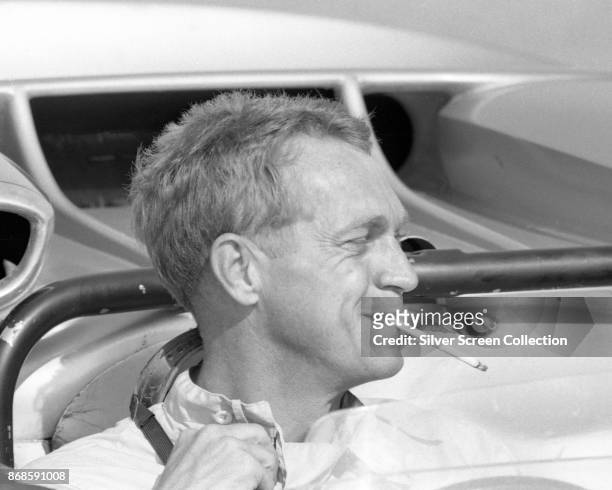 View of American actor Steve McQueen , a cigarette in his mouth, as he sits in car at Riverside Raceway, Riverside, California, July 1966.