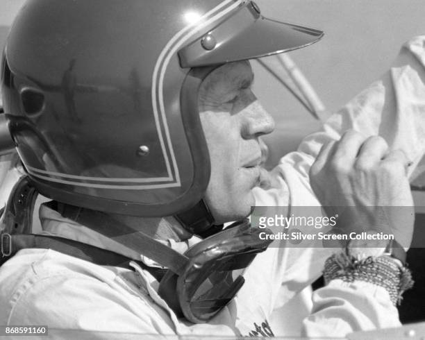 View of American actor Steve McQueen , in Firestone racing suit, as he sits in a car at Riverside Raceway, Riverside, California, July 1966.