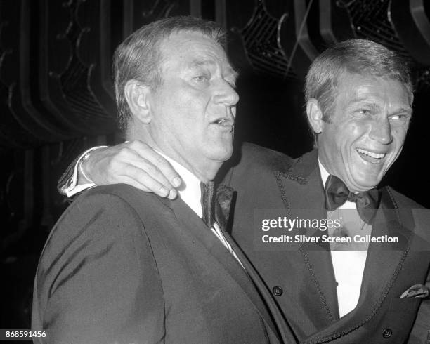 American actors John Wayne and Steve McQueen share a laugh during the 24th Annual Golden Globe Awards ceremony at the Cocoanut Grove, Los Angeles,...