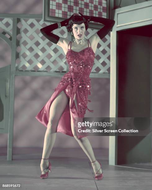American actress and dancer Cyd Charisse , in black elbow gloves and a red, sequin dress, dances in a scene from the film 'The Band Wagon' , Culver...