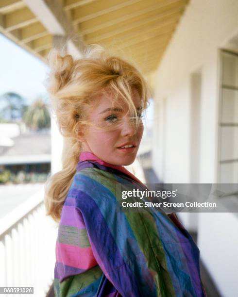 Portrait of American actress Tuesday Weld, in a striped top, as she poses on a windy balcony, 1960s.