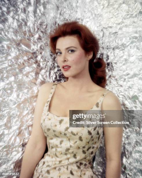 Portrait of American actress Tina Louise , in a flower-print dress, as she poses against a silver backdrop, early 1960s.