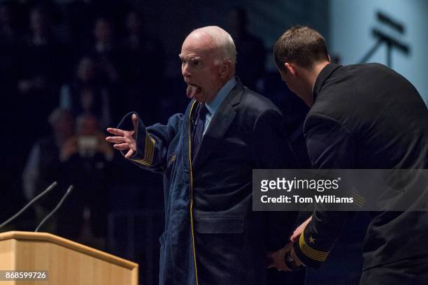 Sen. John McCain, R-Ariz., dons a Navy bath robe given to him by MIDN Brigade Commander Austin Harmel, right, during a ceremony where McCain and...