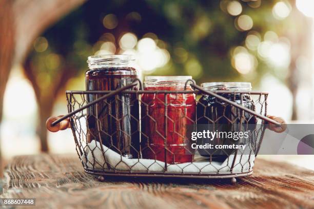 three jars of jam on garden table - strawberry jam stock pictures, royalty-free photos & images