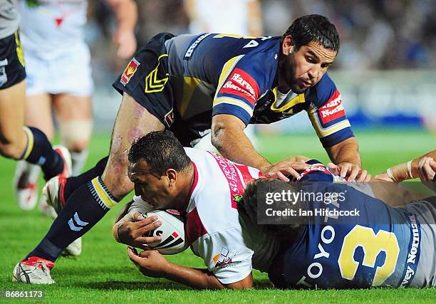 Neville Costigan of the Dragons is wrapped up by the Cowboys defence during the round nine NRL match between the North Queensland Cowboys and the St...