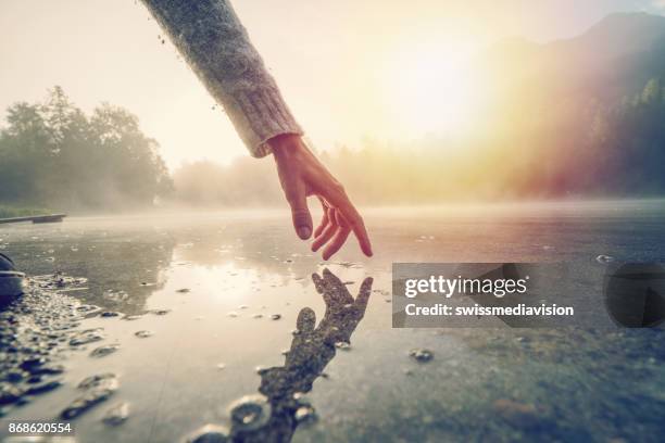 dedo toca a superfície do lago na montanha, suíça - sunrise contemplation - fotografias e filmes do acervo