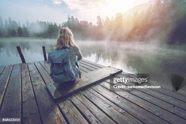 meisje van de berg genieten van ochtend mist vanaf lake pier, zon stijgen - bergsteiger stockfoto's en -beelden