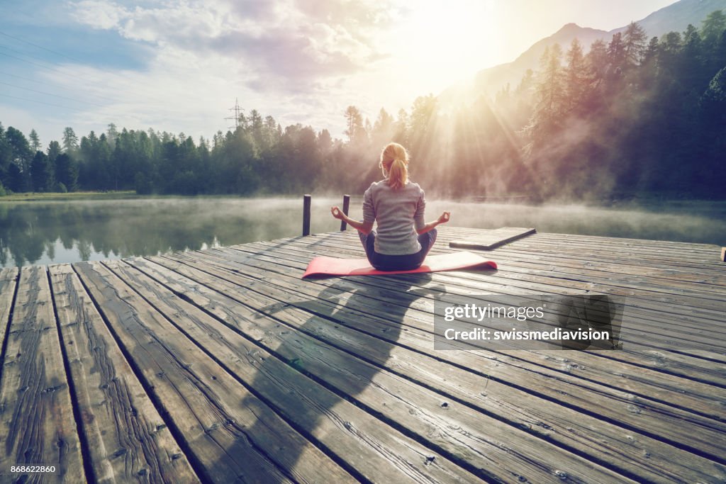 Kaukasische Mädchen Ausübung Yoga in der Natur, Morgen am See in der Schweiz