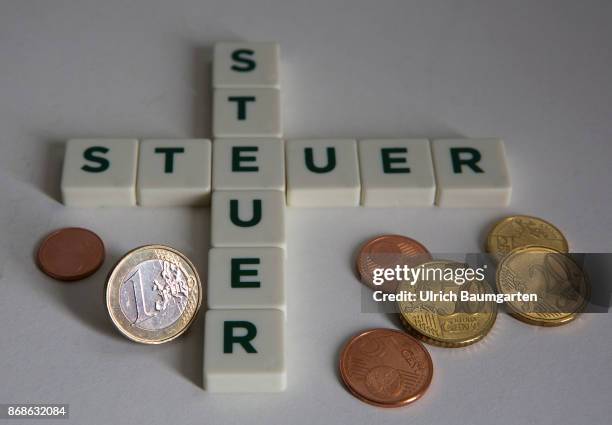 Symbol photo on the subject of taxes. The photo shows the words taxe, placed from scrabble stones, and different euro coins.