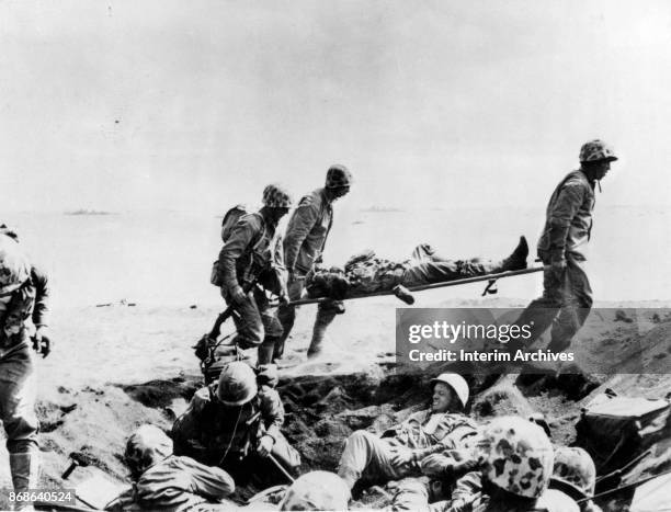 United States Marines carry a wounded soldier on a stretcher along a beach during the Battle of Iwo Jima, Iwo Jima, Japan, 1945.