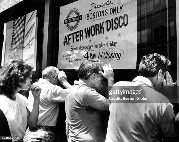 Passersby peer into the Blackfriars lounge at 105 Summer St. In Boston, where the bodies of five men were found in the basement office, on Jun. 28,...