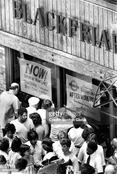 Crowds peer into the Blackfriars lounge at 105 Summer St. In Boston, where the bodies of five men were found in the basement office, on Jun. 28,...
