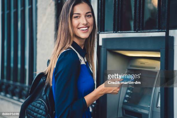 frau mit geld am geldautomaten zurückziehen - account money lifestyle stock-fotos und bilder