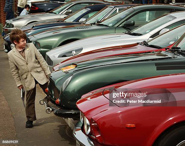 Boy looks at a line of of Aston Martin cars parked at the Aston Martin Works Service factory during an auction held by Bonham's on May 9, 2009 in...