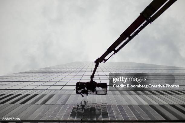 window washers clean the exterior of a building in new york - cherry picker stock pictures, royalty-free photos & images
