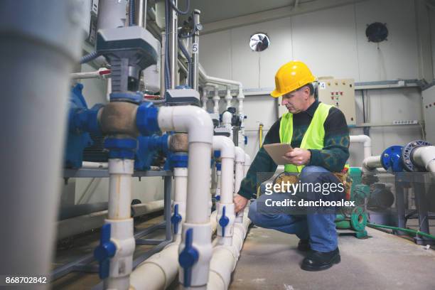 senior repairman in boiler room checking pipes - heat stress stock pictures, royalty-free photos & images