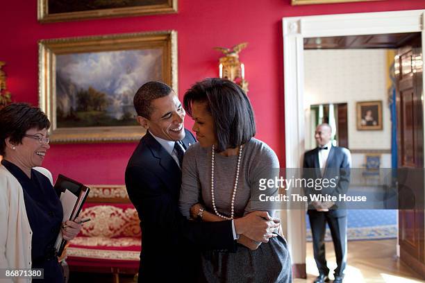 In this handout provide by the White House, U.S. President Barack Obama hugs First Lady Michelle Obama in the Red Room while Senior Advisor Valerie...
