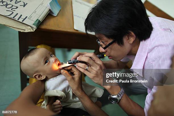 Burmese doctor examines a baby with AIDS a at a special clinic for AIDS on April 29, 2009 in Yangon, Myanmar . The situation for many people living...