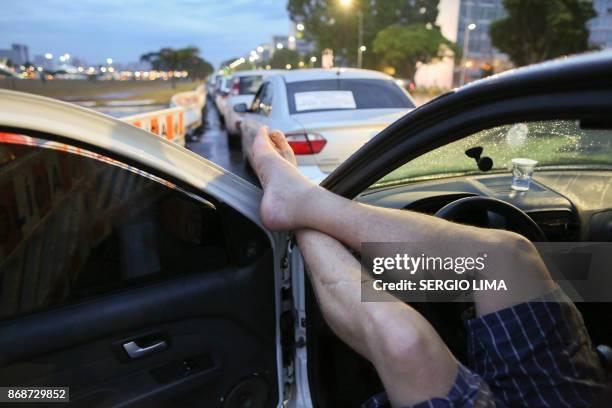 Drivers of companies Uber, Cabify and 99 Taxi wait as the Senate votes on a project to regulate the ride-sharing companies, in Brasilia on October...