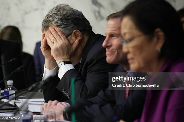 Senate Judiciary Committee member Sen. Al Franken covers his face in frustration as he questions witnesses from Google, Facebook and Twitter during a...