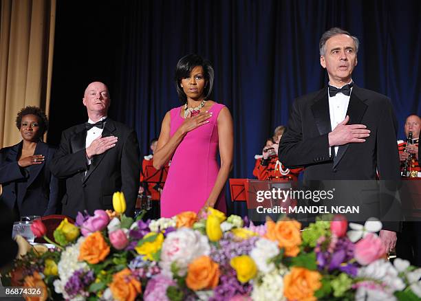 First Lady Michelle Obama listens to the national anthem with from left, comic actress Wanda Sykes, photographer Doug Mills of the New York Times and...