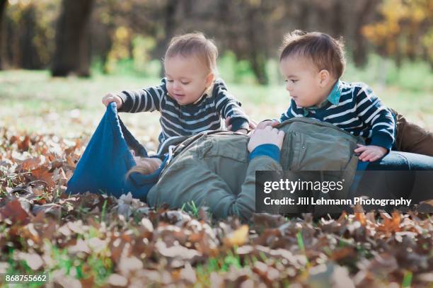 mother plays "peek" with fraternal twins outside on an autumn day - iowa family stock pictures, royalty-free photos & images