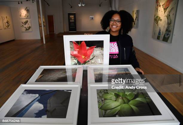 Pablove Foundation program manager and photographer Ashley Blakeney displays photographs taken by local area kids living with cancer at the Artwork...