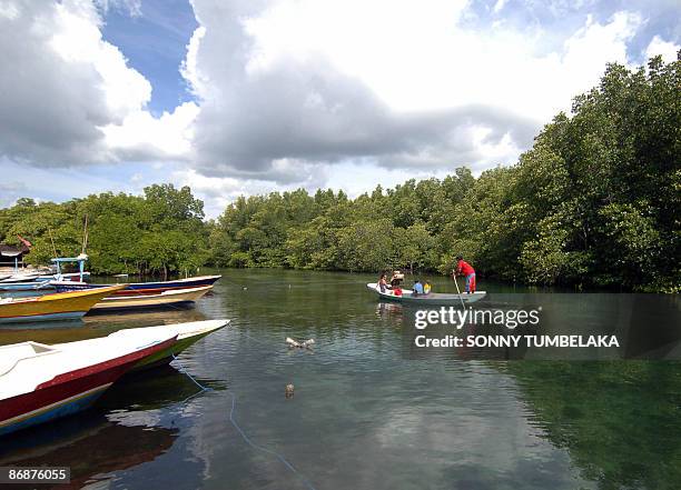 By Aubrey Belford A small boat carries tourists through a lush mangrove during a tour around Nusa Penida on the Indonesian resort island of Bali on...
